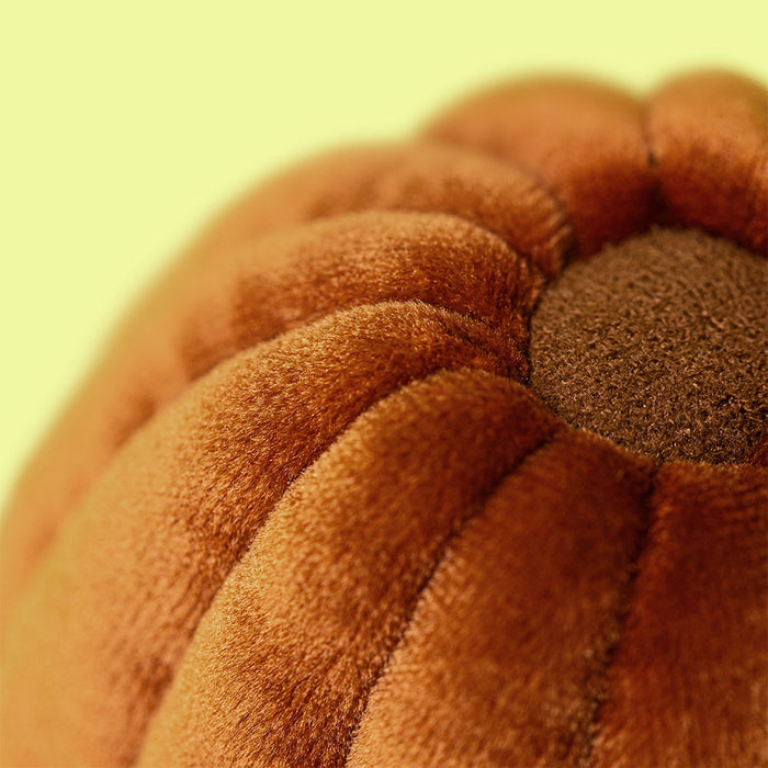 Close up of a brown velvet pumpkin shaped cushion