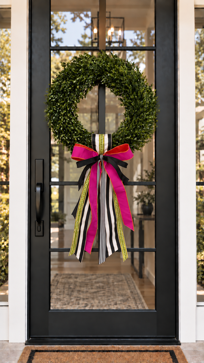 Beetlejuice sash and bow on a boxwood wreath on a black glass front door