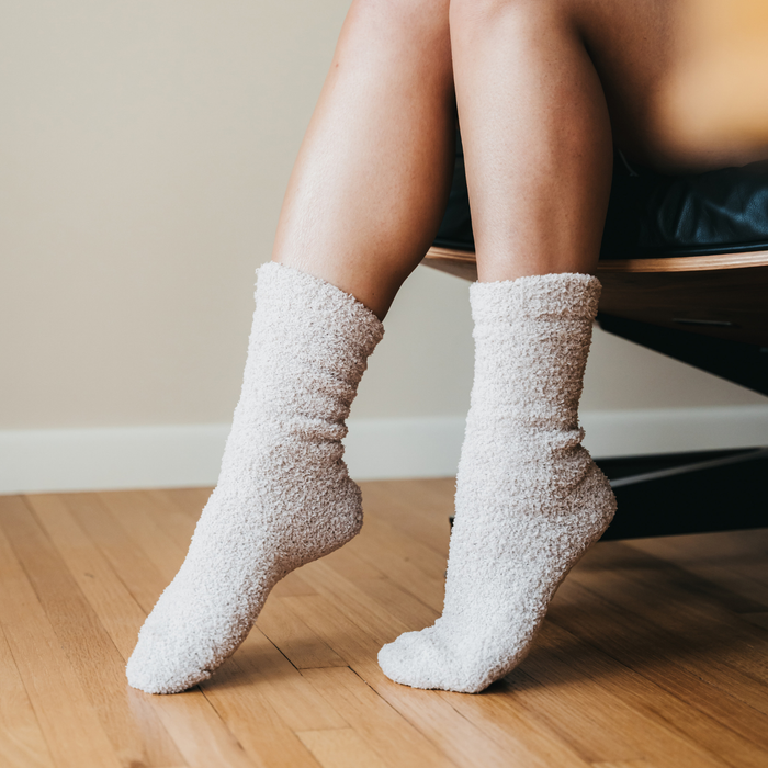 Person wearing beige fuzzy crew socks sitting on a chair