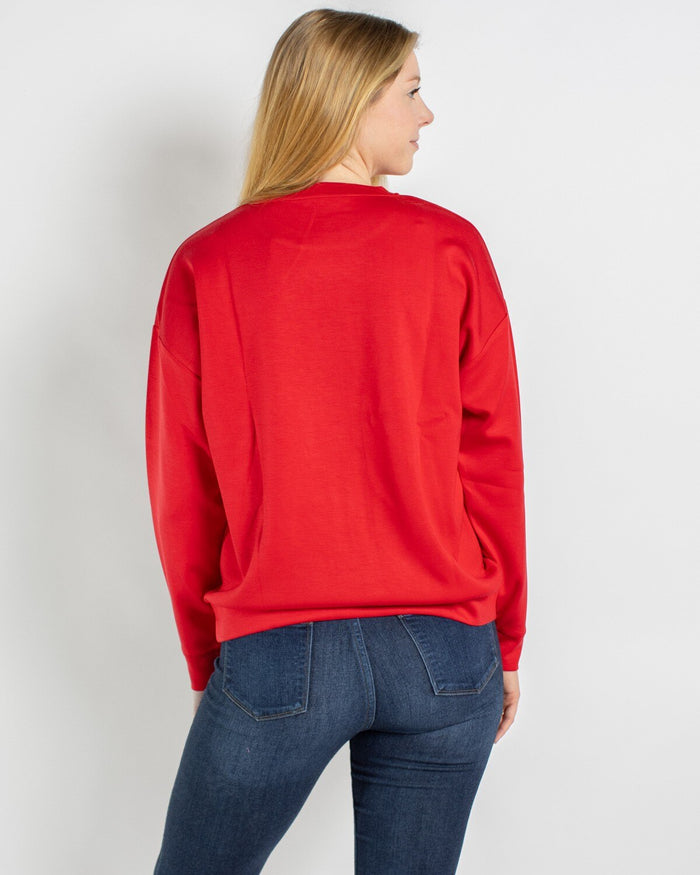 Back view of a person wearing a red crew neck sweatshirt and blue jeans