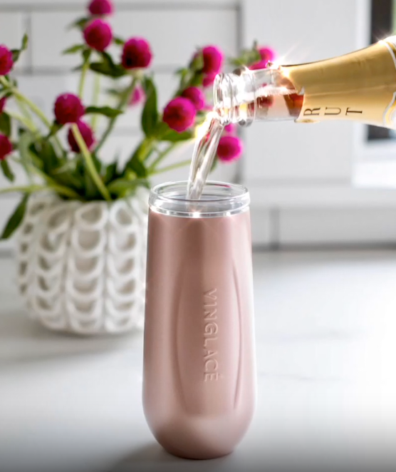 Champagne pouring into a rose gold insulated flute with a lid