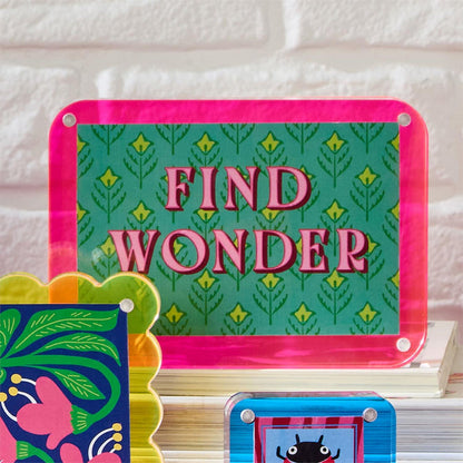 Pink and green Find Wonder acrylic frame on a shelf