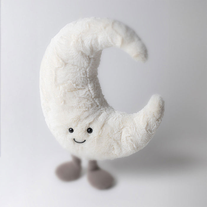 Crescent moon plush toy with a smiling face and small grey feet