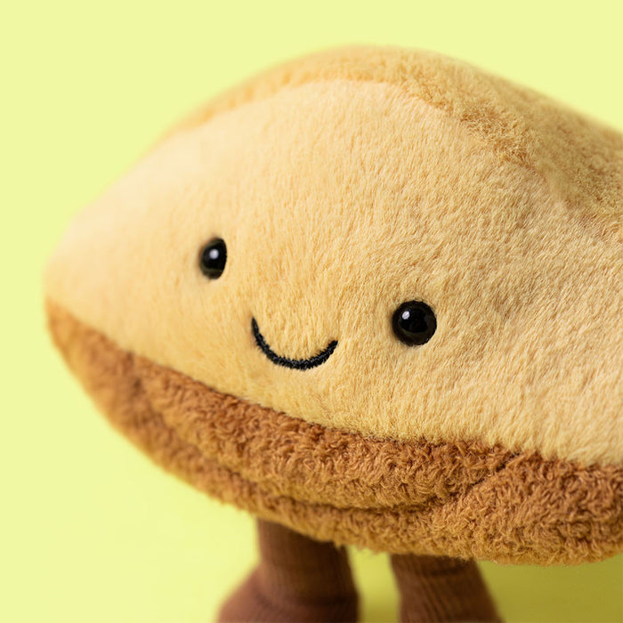 Tan plush toy shaped like a mushroom cap with black embroidered eyes and a smile