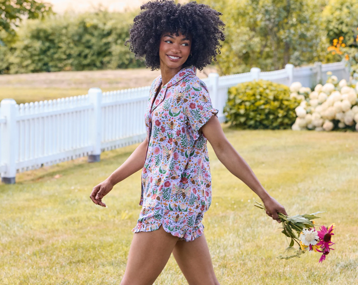 Woman in a bee print pajama set walking in a garden