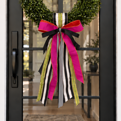 Door sash and bow in hot pink, black and white stripe and chartreuse ribbon on a boxwood wreath