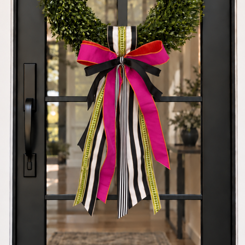 Door sash and bow in hot pink, black and white stripe and chartreuse ribbon on a boxwood wreath