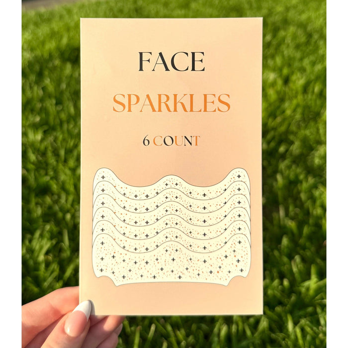 Hand holding a pack of Face Sparkles adhesive face gems in black and gold