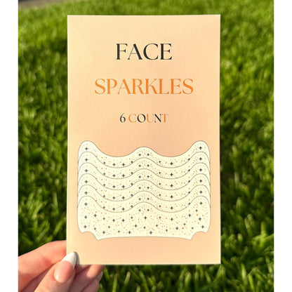 Hand holding a pack of Face Sparkles adhesive face gems in black and gold