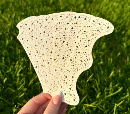 Hand holding a sheet of adhesive face sparkle gems over grass