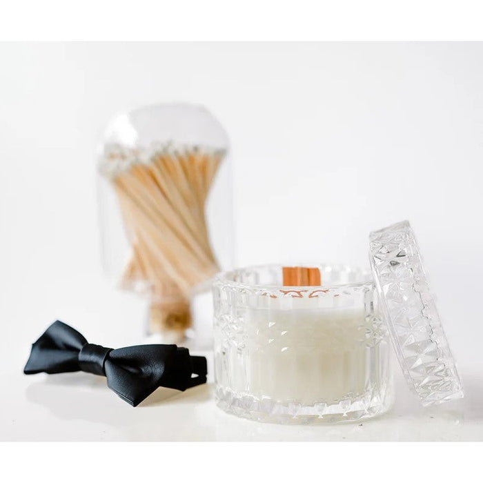 Glass candle jar with lid, black bow tie, and glass cloche filled with matches