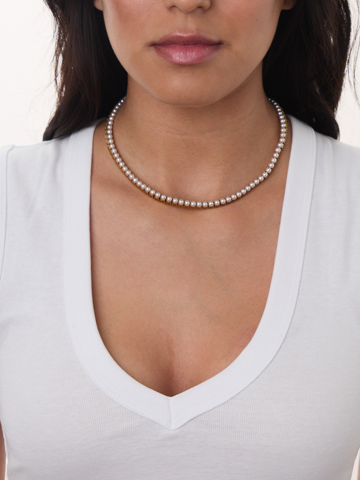 Model wearing a gold 4mm pearl necklace with a white top