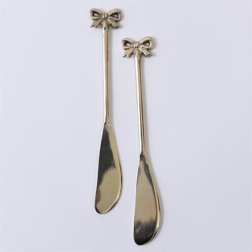 Two gold spreaders with bow-topped handles