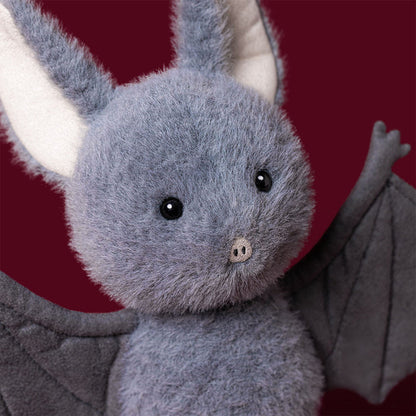 Close-up of a gray bat plush's face and wing