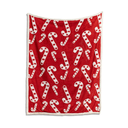 Red throw blanket with a white candy cane pattern and white sherpa trim