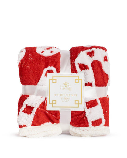 Folded red and white patterned throw blanket with a product label