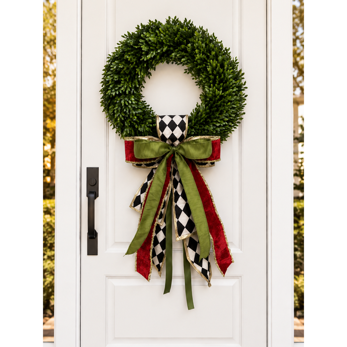 White front door with a boxwood wreath and a harlequin, olive green and red ribbon bow