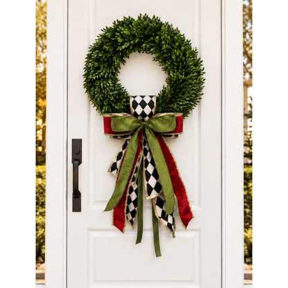 White front door with a boxwood wreath and a harlequin, olive green and red ribbon bow