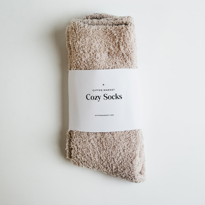 Beige fuzzy socks wrapped in a white paper band with Giften Market branding