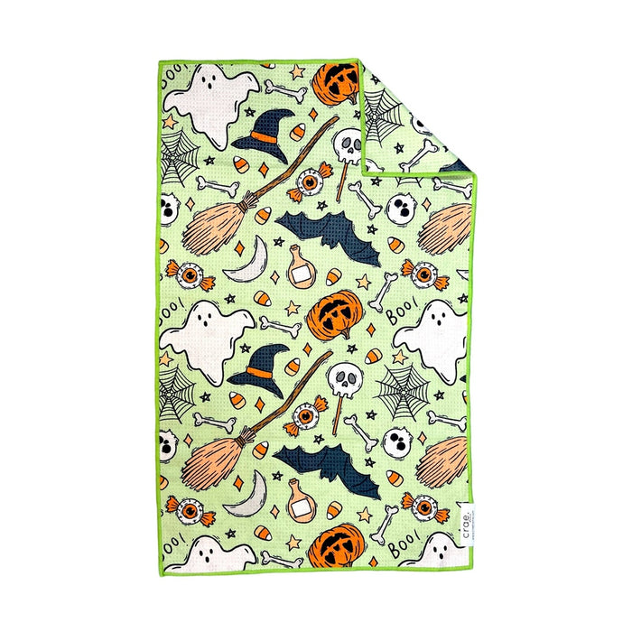 Lime green hand towel printed with witch hats, brooms, bats, ghosts and candy