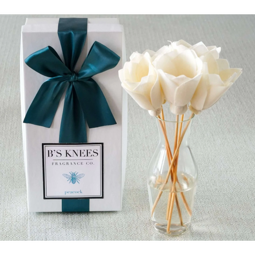 White gift box with teal ribbon and B's Knees Fragrance Co label next to a glass vase with white flower reed diffusers