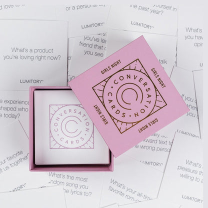 Pink Lumitory conversation cards box open on a surface covered with scattered question cards