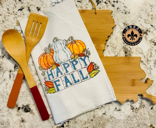 Happy Fall tea towel with pumpkins, styled with wooden spoons on a Louisiana-shaped board