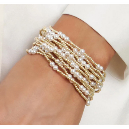 Stack of gold and pearl beaded bracelets on a wrist
