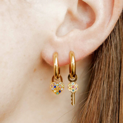 Model wearing gold huggies with lock and key charms