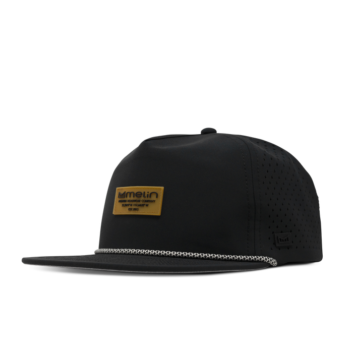 Black five panel snapback hat with perforated side panels and a tan branded patch on the front