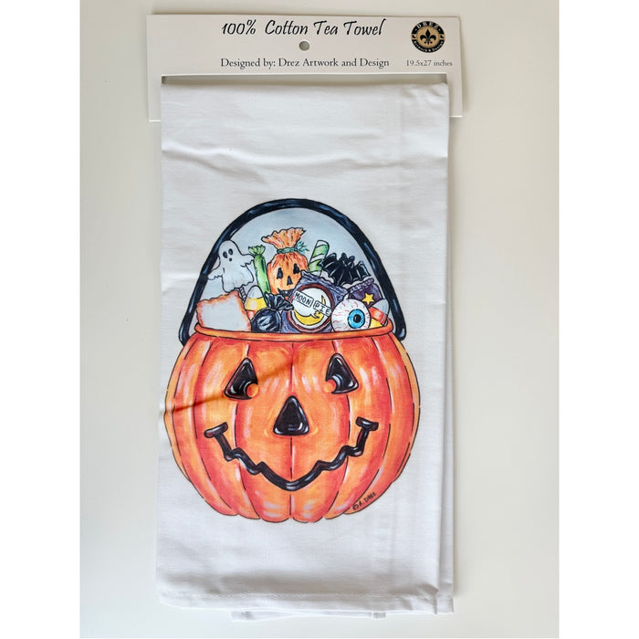 Cotton tea towel printed with a jack-o'-lantern candy bucket overflowing with treats