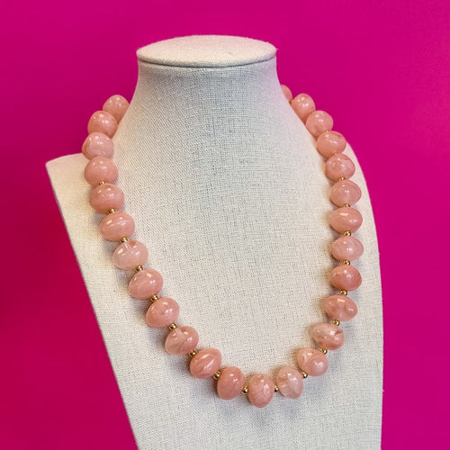 Light pink bauble bead necklace with gold beads on a display bust