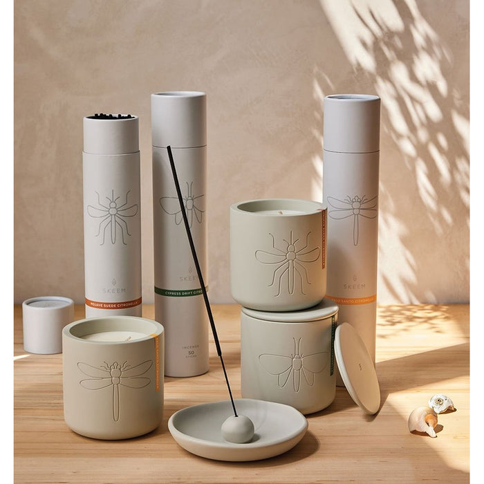 Modern Citronella candles, incense tubes and a burning incense stick in gray ceramic