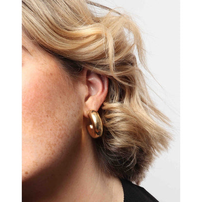 Model wearing chunky gold tube hoops