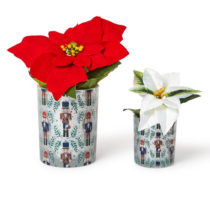 Two glass vases with nutcracker and leaf patterns containing red and white poinsettia flowers
