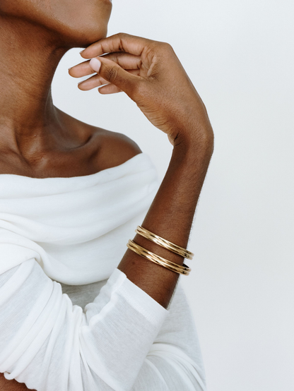 Model wearing stacked gold double-band cuffs