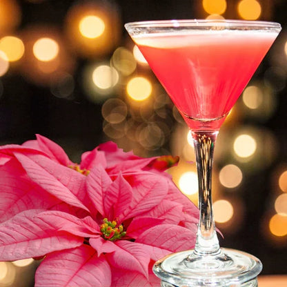 Pink cocktail in a martini glass next to a pink poinsettia plant