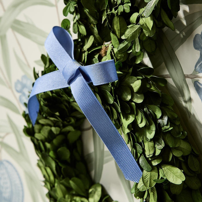 Close-up of a blue ribbon bow on a boxwood wreath