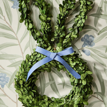 Bunny-shaped boxwood wreath with a blue bow on floral wallpaper