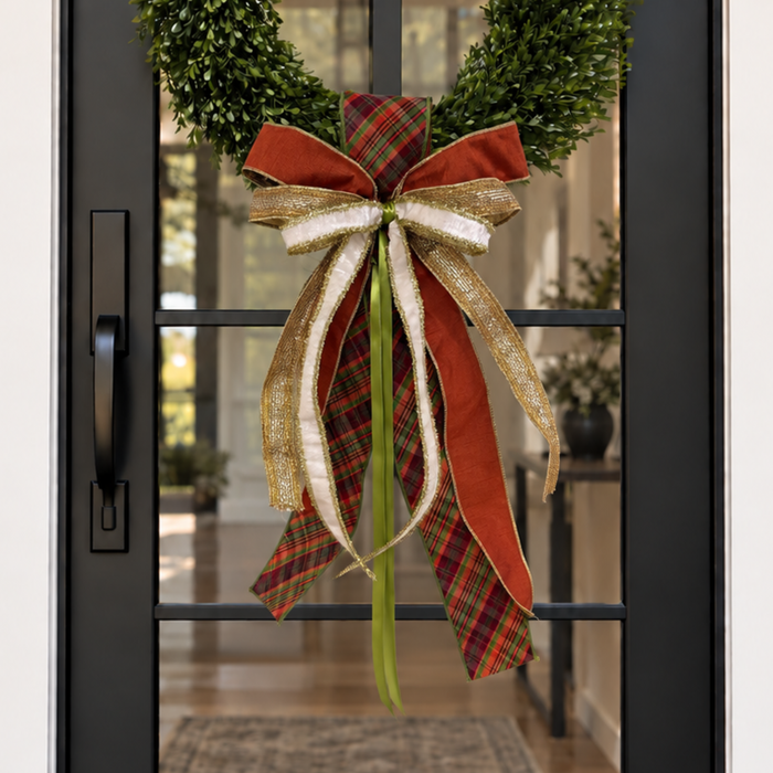 Door sash and bow in rust plaid, cream and gold ribbon on a boxwood wreath