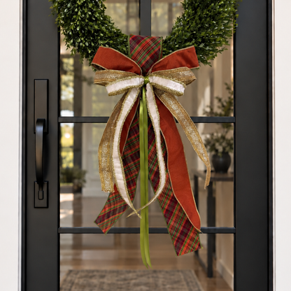 Door sash and bow in rust plaid, cream and gold ribbon on a boxwood wreath