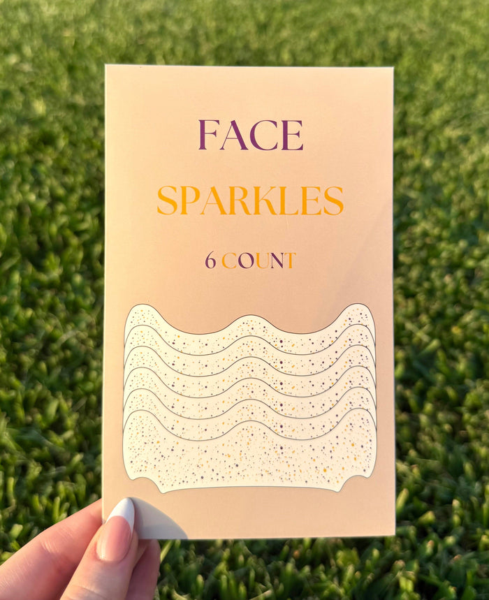 Hand holding a pack of Face Sparkles adhesive face gems in purple and gold