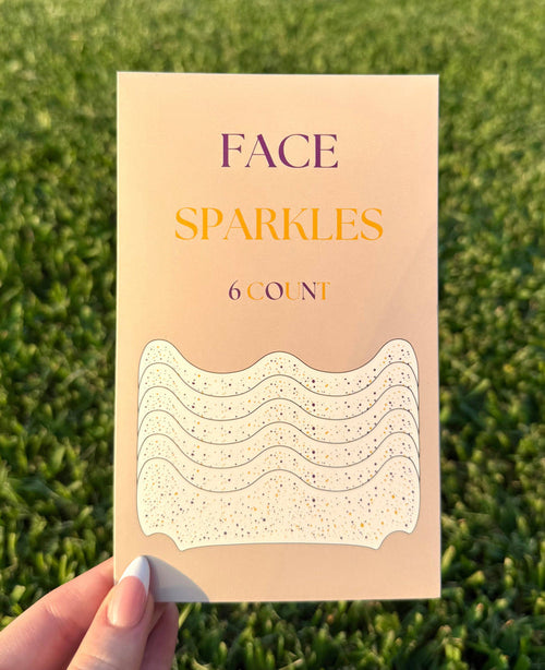 Hand holding a pack of Face Sparkles adhesive face gems in purple and gold