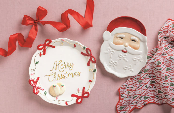 Merry Christmas plate with Santa shaped dish and holiday patterned napkin on pink background