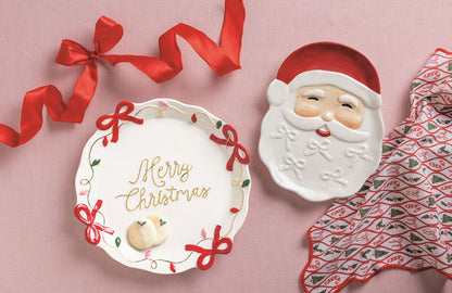 Merry Christmas plate with Santa shaped dish and holiday patterned napkin on pink background