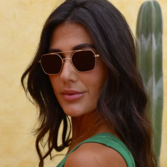 Woman by a cactus wearing gold hexagon sunglasses