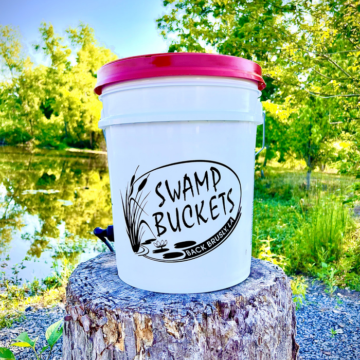 White Swamp Buckets bucket with a pink lid on a stump by the water