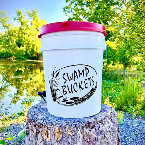 White Swamp Buckets bucket with a pink lid on a stump by the water