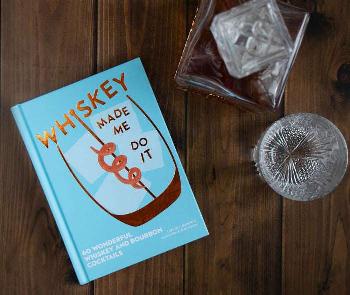 Whiskey Made Me Do It cocktail book with rocks glasses on wood