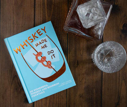 Whiskey Made Me Do It cocktail book with rocks glasses on wood